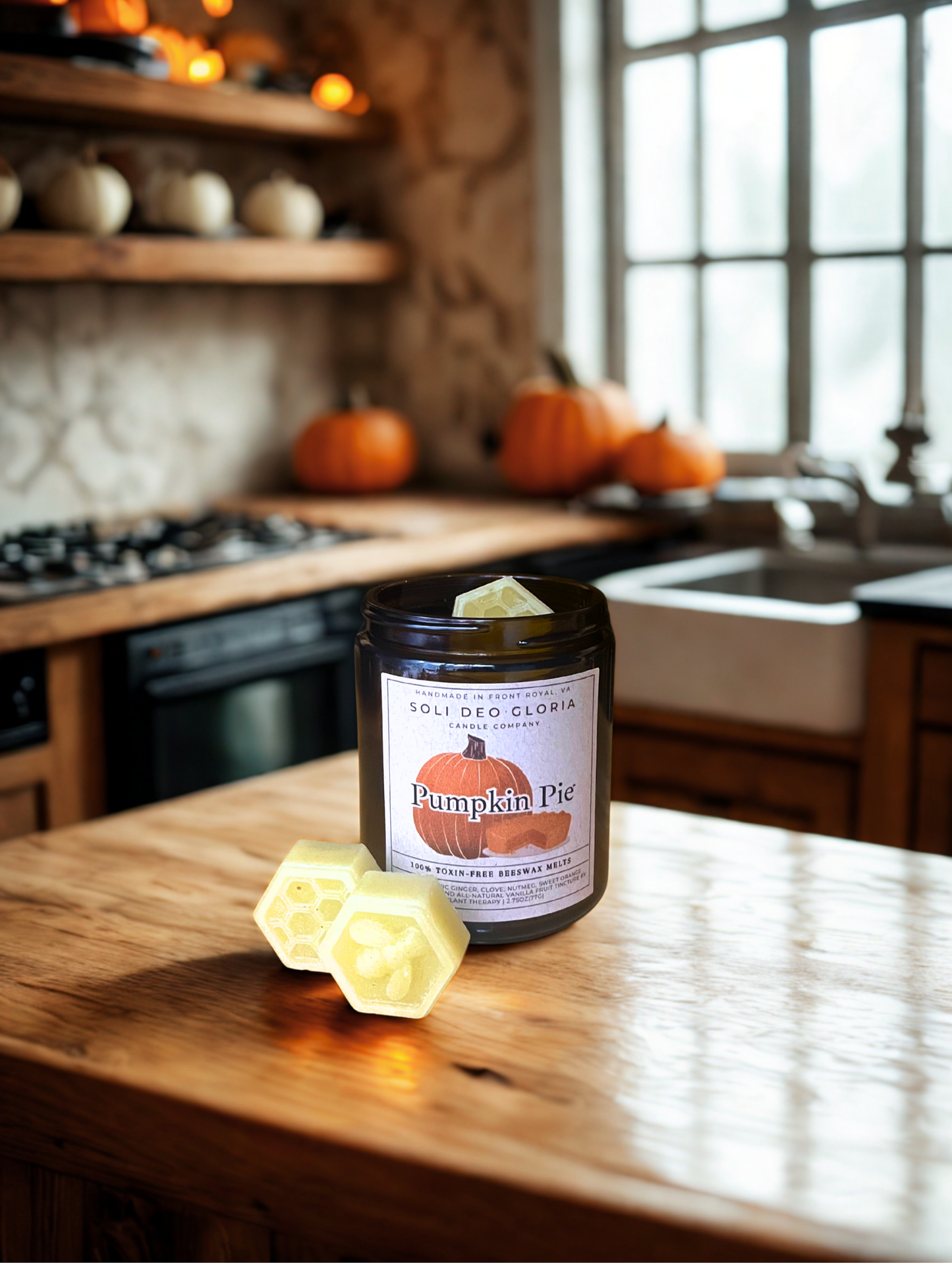 Candle labeled 'Pumpkin Pie' on a kitchen counter with pumpkins in the background