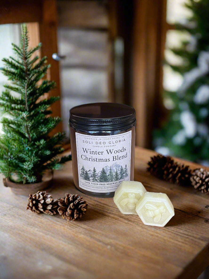 Candle labeled 'Winter Woods Christmas Blend' on a wooden surface with decorative elements.