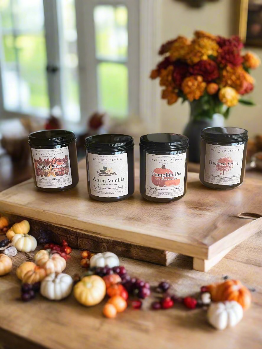 Four candles with labels on a wooden table in a home setting