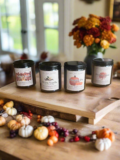 Four candles with labels on a wooden table in a home setting