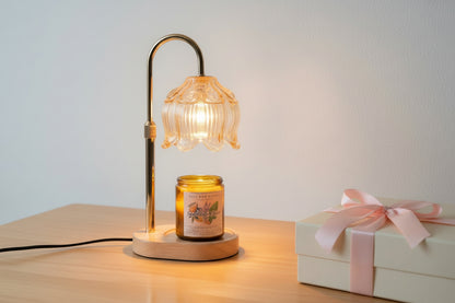 Table candle lamp with a candle on a wooden surface next to a gift box.